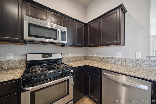 kitchen with dark brown cabinets, appliances with stainless steel finishes, and light stone counters