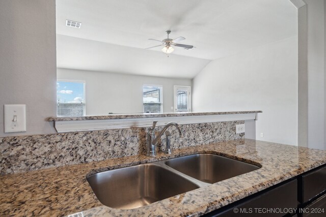 kitchen featuring lofted ceiling, sink, light stone counters, and ceiling fan