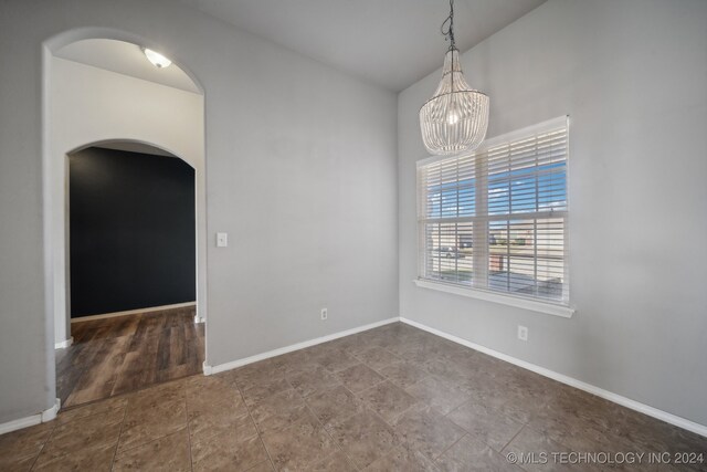 unfurnished room with a notable chandelier