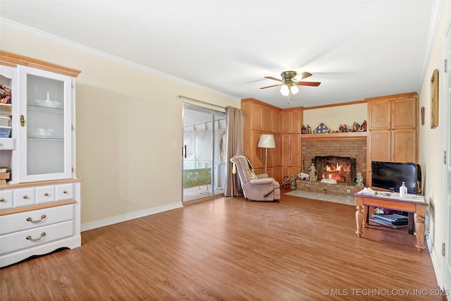 living area with light hardwood / wood-style floors, crown molding, a brick fireplace, and ceiling fan