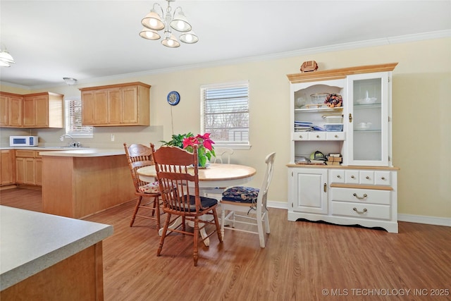 dining space with crown molding, a chandelier, a healthy amount of sunlight, and light hardwood / wood-style floors