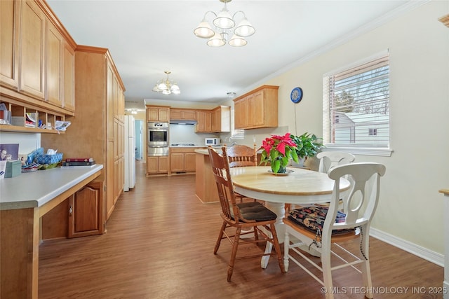 dining area with crown molding, light hardwood / wood-style flooring, and a notable chandelier