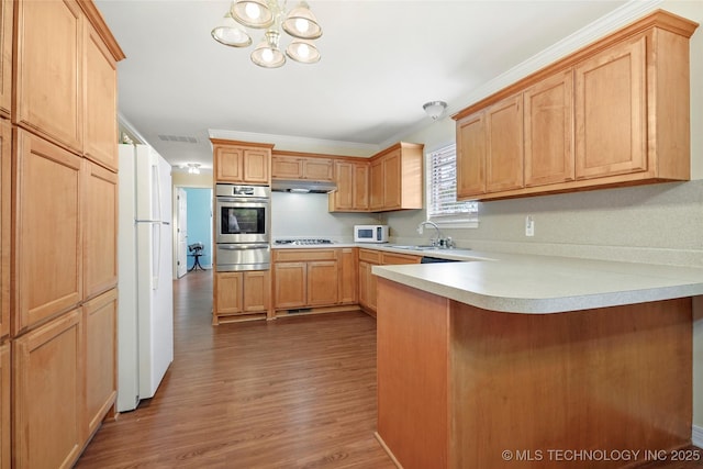 kitchen featuring white appliances, wood-type flooring, sink, ornamental molding, and kitchen peninsula