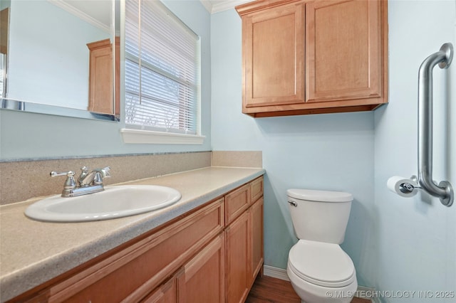 bathroom with toilet, vanity, and crown molding