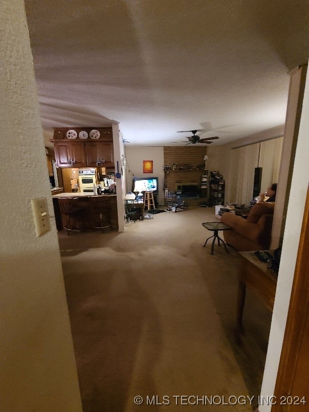 living room with carpet flooring, ceiling fan, and a brick fireplace