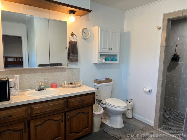 bathroom with tiled shower, ornamental molding, vanity, hardwood / wood-style floors, and toilet