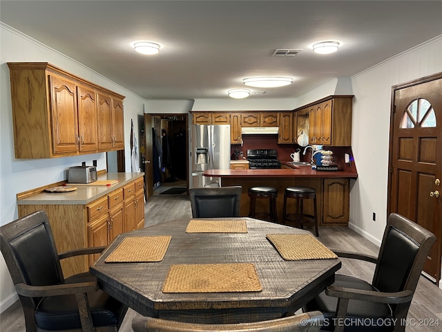 kitchen featuring ornamental molding, stainless steel fridge with ice dispenser, black range with gas cooktop, sink, and dark wood-type flooring