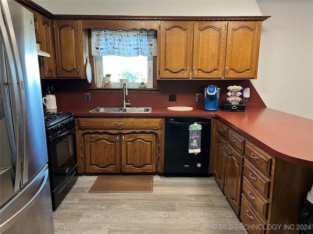 kitchen featuring black appliances, range hood, sink, and light hardwood / wood-style floors