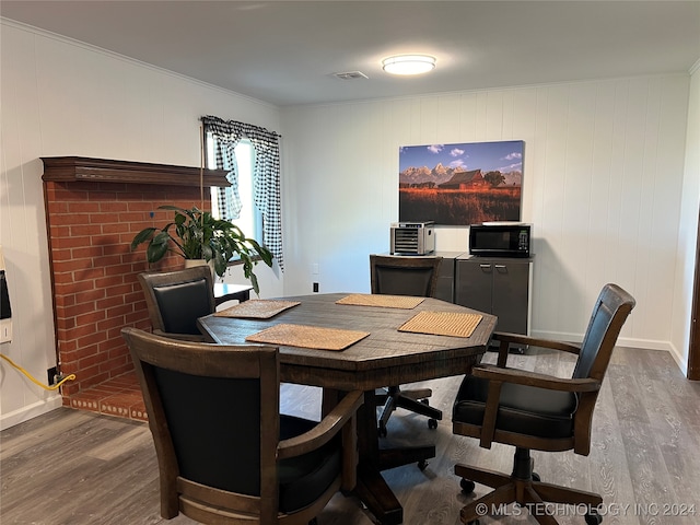 dining space with ornamental molding, wood walls, and hardwood / wood-style flooring