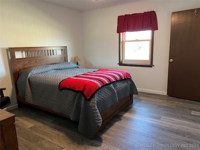 bedroom with dark hardwood / wood-style flooring and ornamental molding