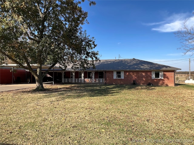 back of house featuring covered porch and a yard