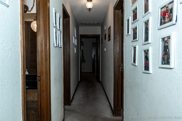 hallway featuring carpet floors and a textured ceiling