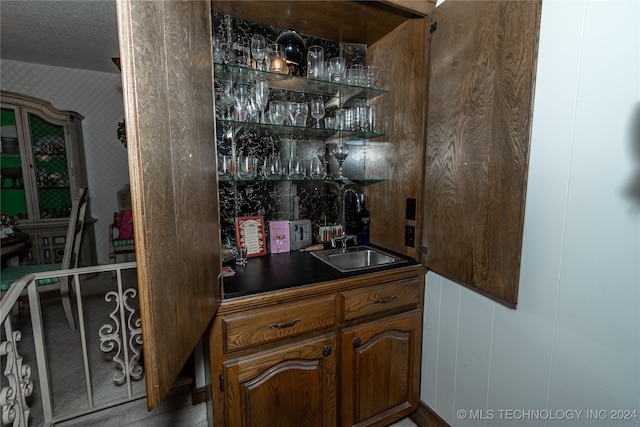 bar featuring wooden walls, sink, and a textured ceiling