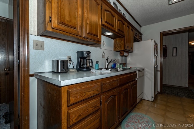 kitchen featuring white appliances, a textured ceiling, and sink