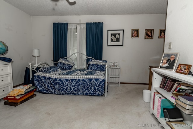 carpeted bedroom featuring ceiling fan and a textured ceiling