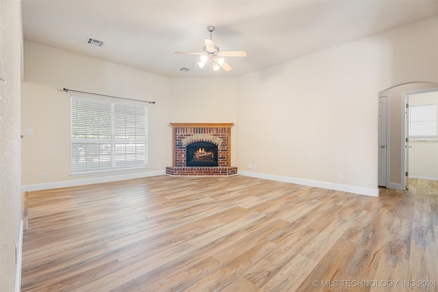 unfurnished living room with a brick fireplace, a wealth of natural light, and light hardwood / wood-style flooring