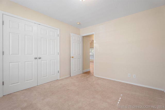 unfurnished bedroom with light colored carpet and a closet