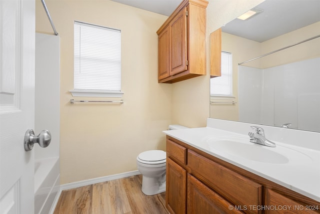 full bathroom with hardwood / wood-style floors, vanity, toilet, and shower / washtub combination