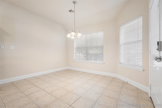 tiled empty room with an inviting chandelier