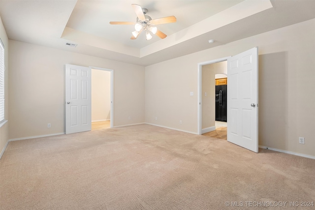 interior space featuring black fridge, light colored carpet, ceiling fan, and a raised ceiling