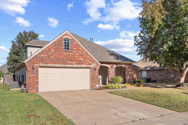 view of property with a garage, cooling unit, and a front lawn