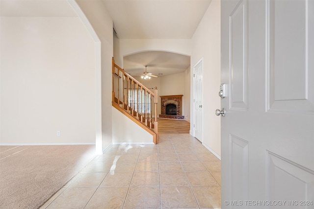 tiled foyer entrance with a fireplace and ceiling fan