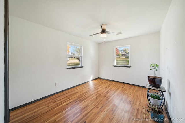 spare room with hardwood / wood-style flooring, a healthy amount of sunlight, and ceiling fan