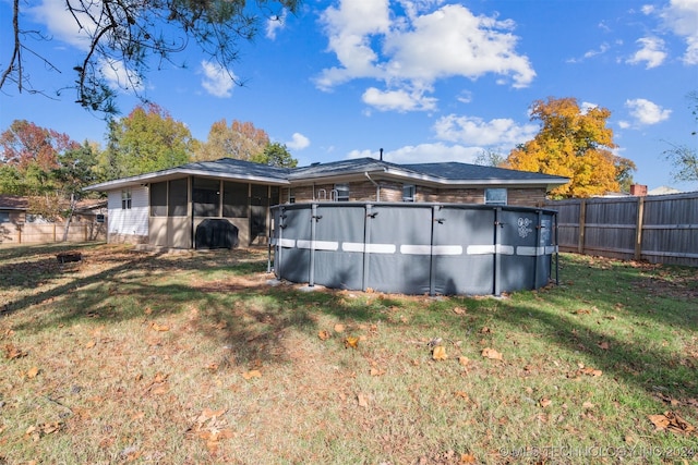 rear view of property with a fenced in pool, a yard, and a sunroom