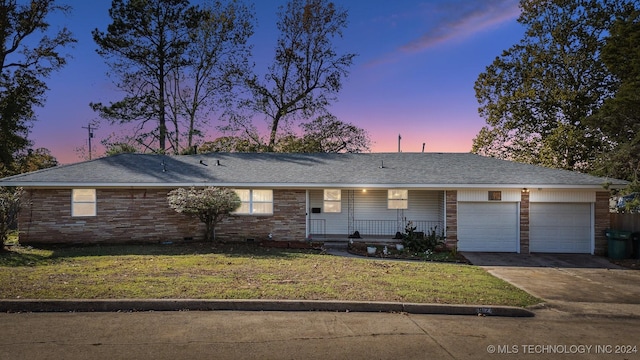 ranch-style home with a garage, a porch, and a yard