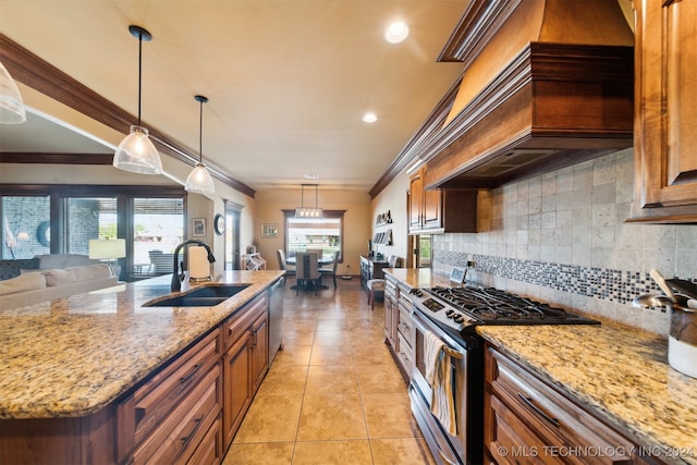 kitchen with pendant lighting, appliances with stainless steel finishes, decorative backsplash, sink, and custom range hood