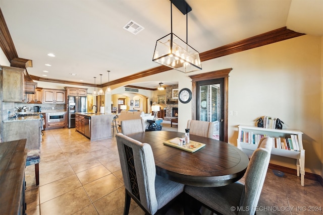 dining room with crown molding, light tile patterned flooring, sink, and ceiling fan with notable chandelier