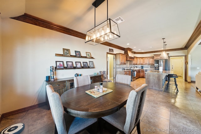 dining room with sink, light tile patterned flooring, and ornamental molding