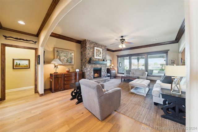 living room with a fireplace, light hardwood / wood-style floors, ceiling fan, and ornamental molding