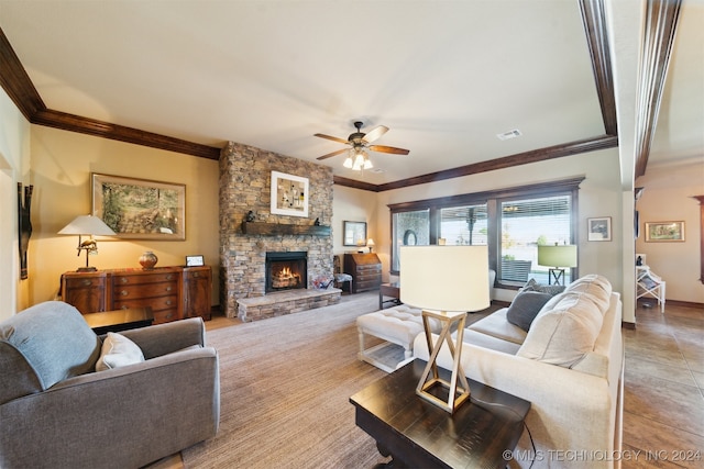 living room featuring ceiling fan, a stone fireplace, and ornamental molding