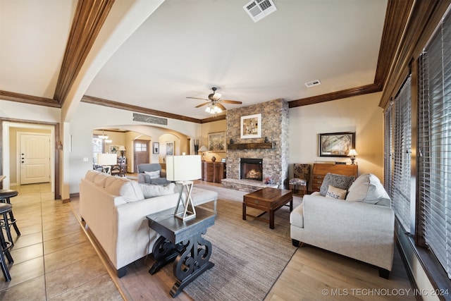 living room with ceiling fan, light hardwood / wood-style flooring, ornamental molding, and a fireplace