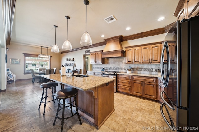 kitchen with gas range, custom range hood, sink, decorative light fixtures, and black fridge