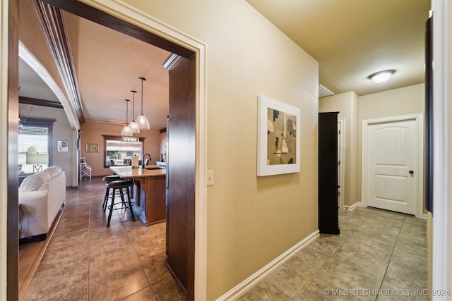 corridor featuring sink, tile patterned flooring, and ornamental molding