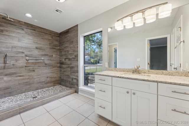 bathroom with a tile shower, vanity, and tile patterned floors