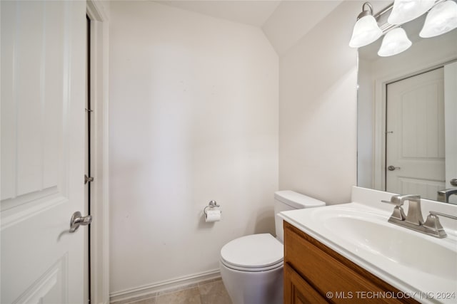 bathroom featuring vanity, tile patterned floors, lofted ceiling, and toilet