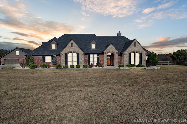 french country style house featuring a garage and a yard