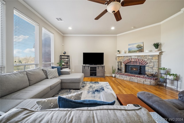 living room with light hardwood / wood-style floors, ceiling fan, a wood stove, and crown molding