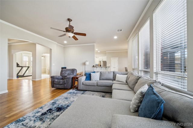 living room with ceiling fan, crown molding, and light hardwood / wood-style flooring