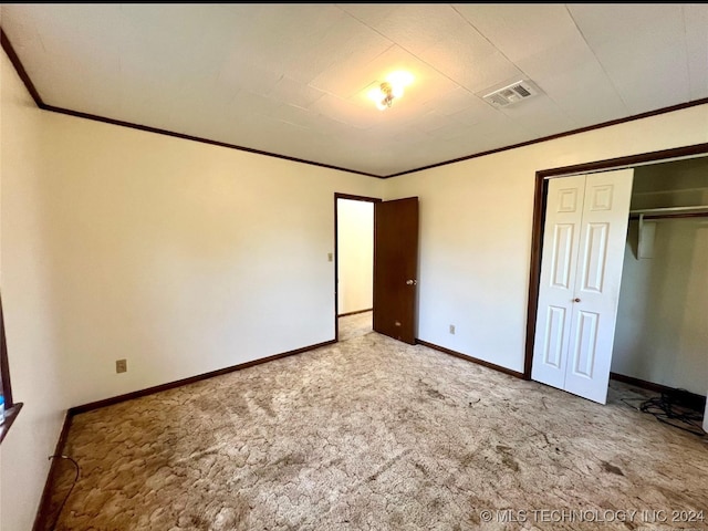 unfurnished bedroom with a closet, carpet flooring, and ornamental molding