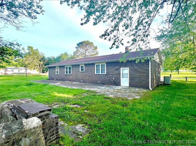 rear view of house featuring central AC and a yard