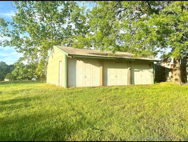 view of outdoor structure featuring a garage and a lawn