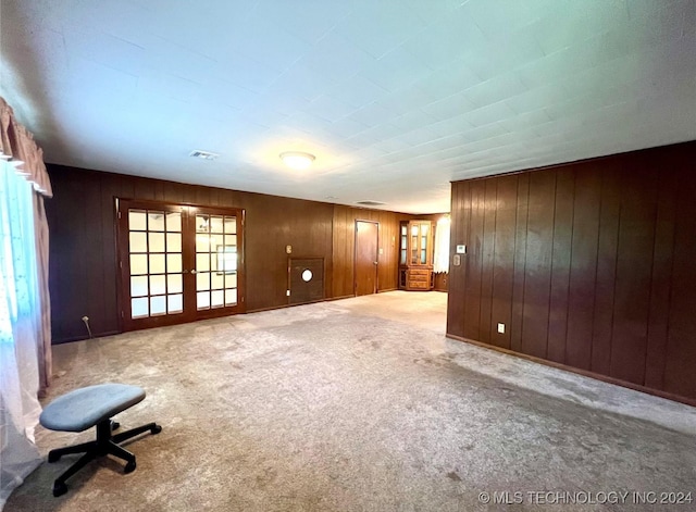 empty room with carpet, wooden walls, and french doors