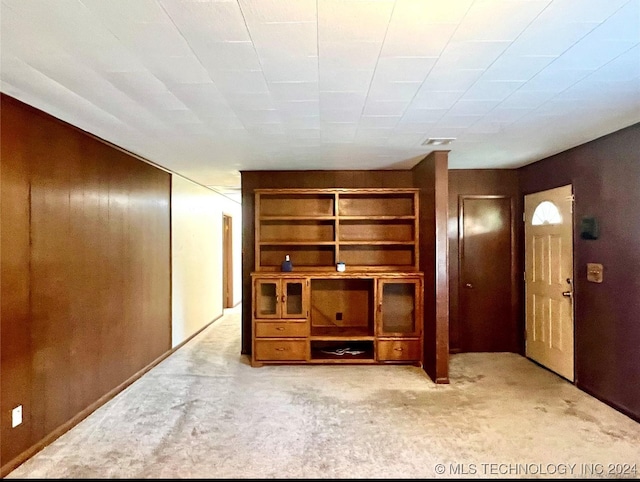 unfurnished living room with wood walls and light carpet