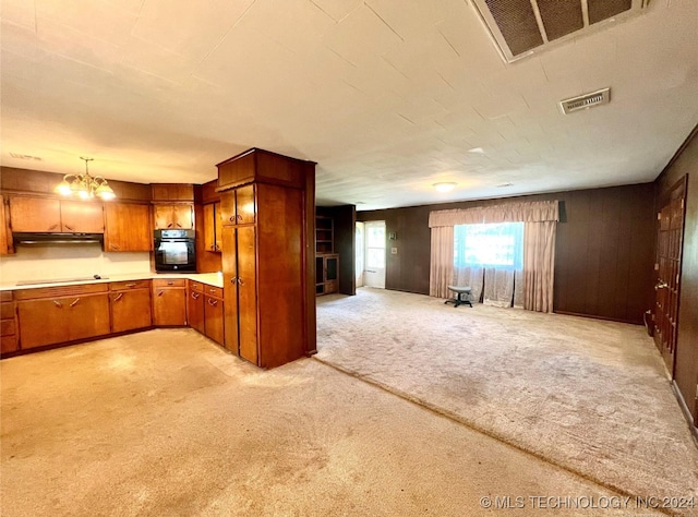 kitchen with light carpet, stovetop, black oven, a chandelier, and pendant lighting