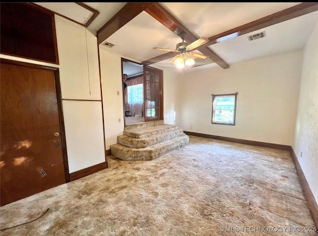 unfurnished living room with beamed ceiling, ceiling fan, and carpet floors