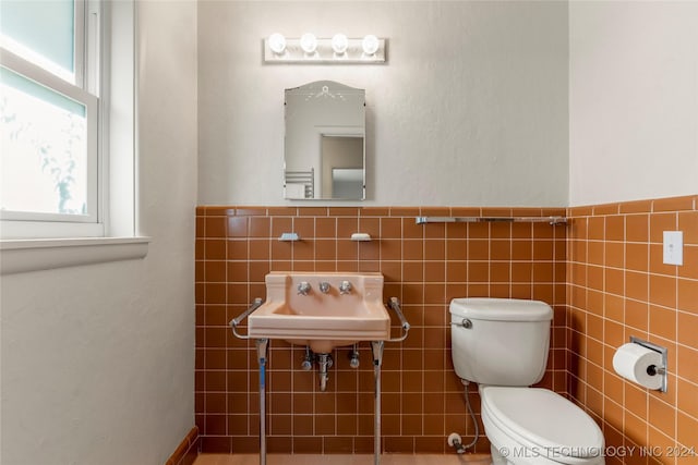 3920 S Utica Ave, Tulsa, OK 74105 - bathroom featuring toilet, tile walls, a sink, and a wainscoted wall